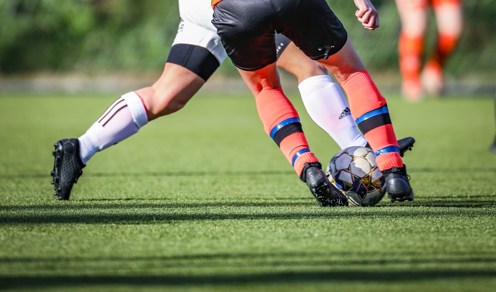 Image of Woman in soccer jersey kicking the ball on a green field